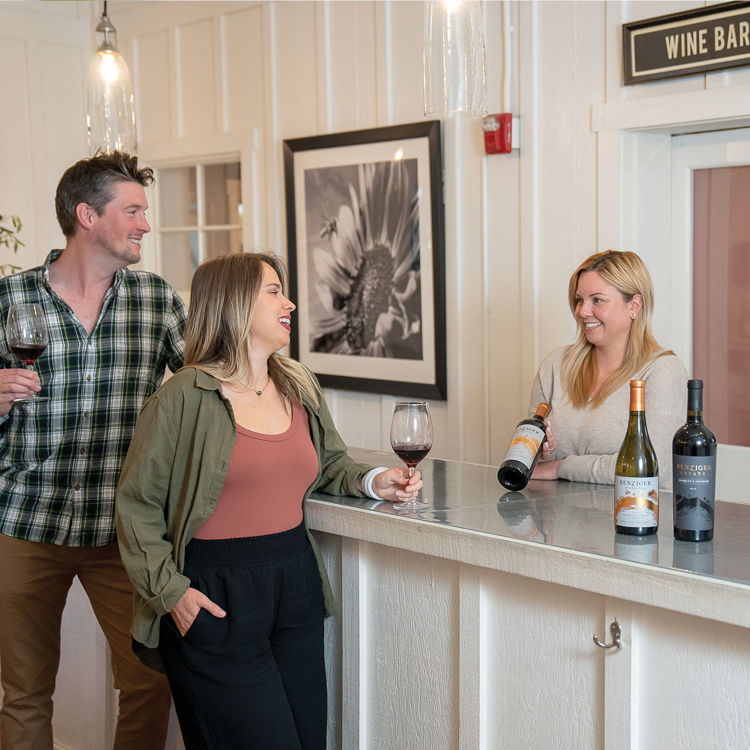 Tasting room associate showing two people a Benziger wine bottle