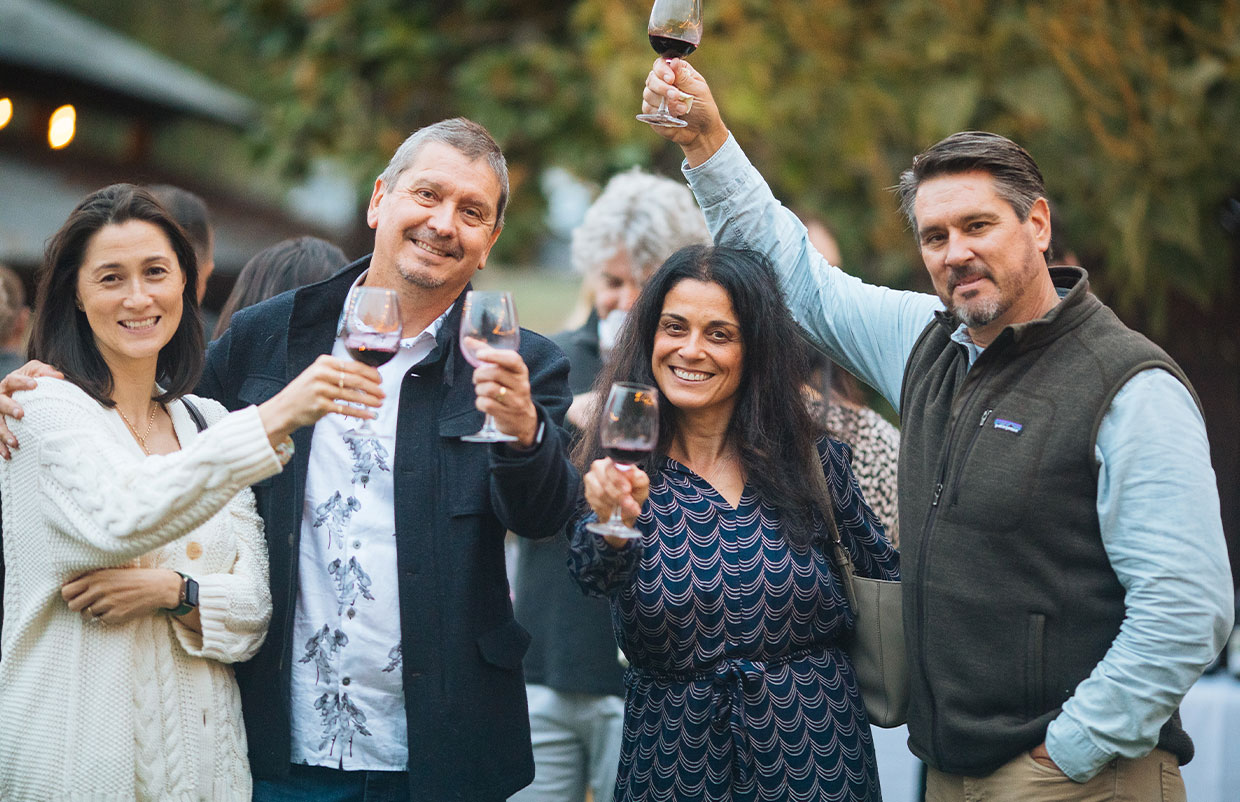 Four people holding wine glasses posing together
